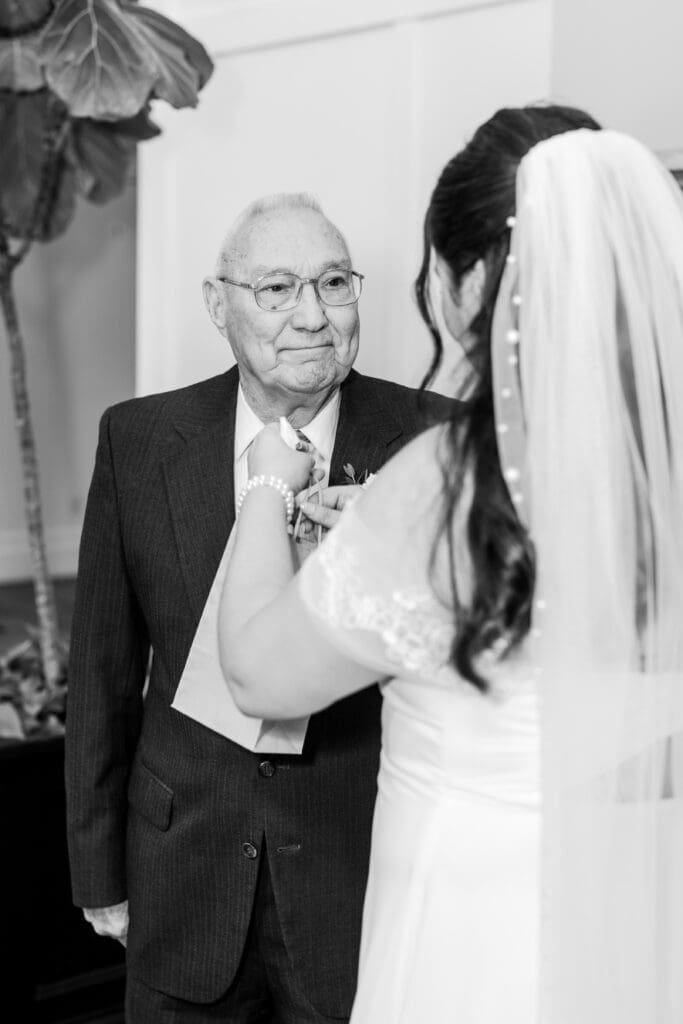 The bride's grandpa looking lovingly at her as she gives him a gift during their first look.