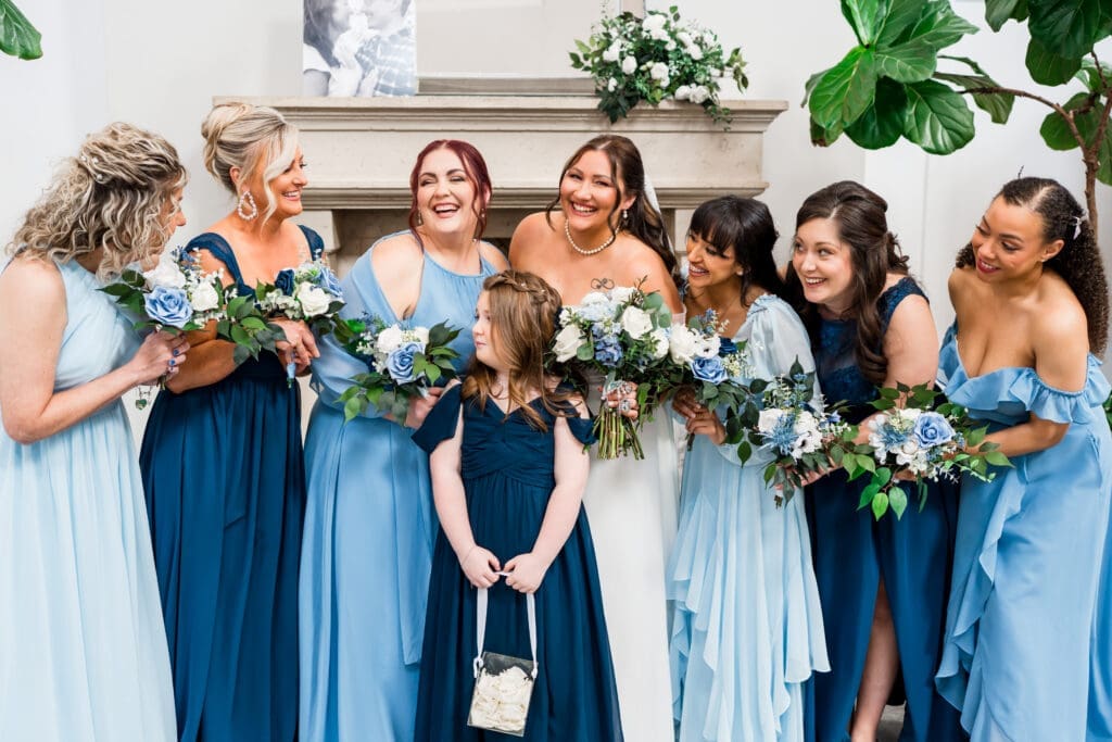 The bride and her bridesmaids in blue laugh at each other at the Estate at new Albany.