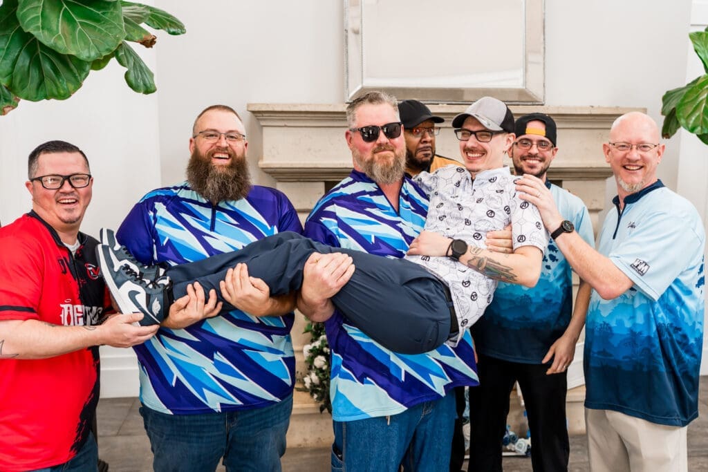 Groomsmen pose in their bowling jerseys holding up the groom at The Estate at New Albany.