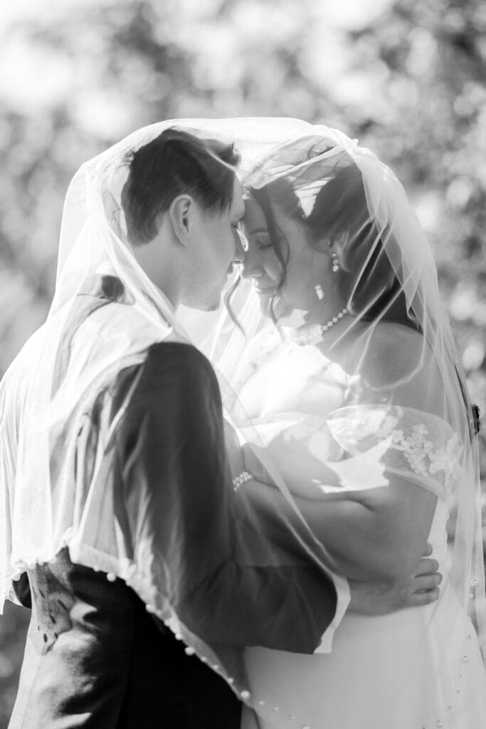 The couple rests their foreheads together and close their eyes underneath the bride's veil at the Estate at New Albany