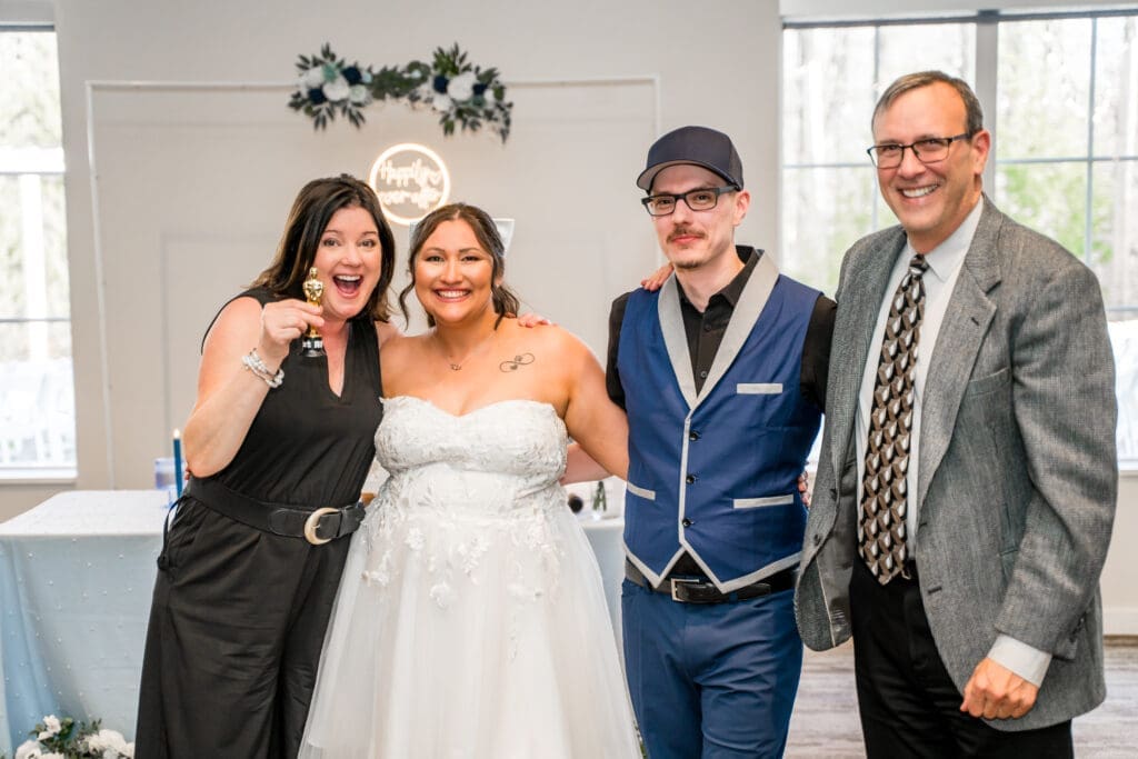 Guest holds up a mini trophy and poses with the couple
