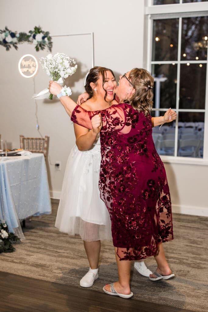 The bride and her aunt laugh and hug