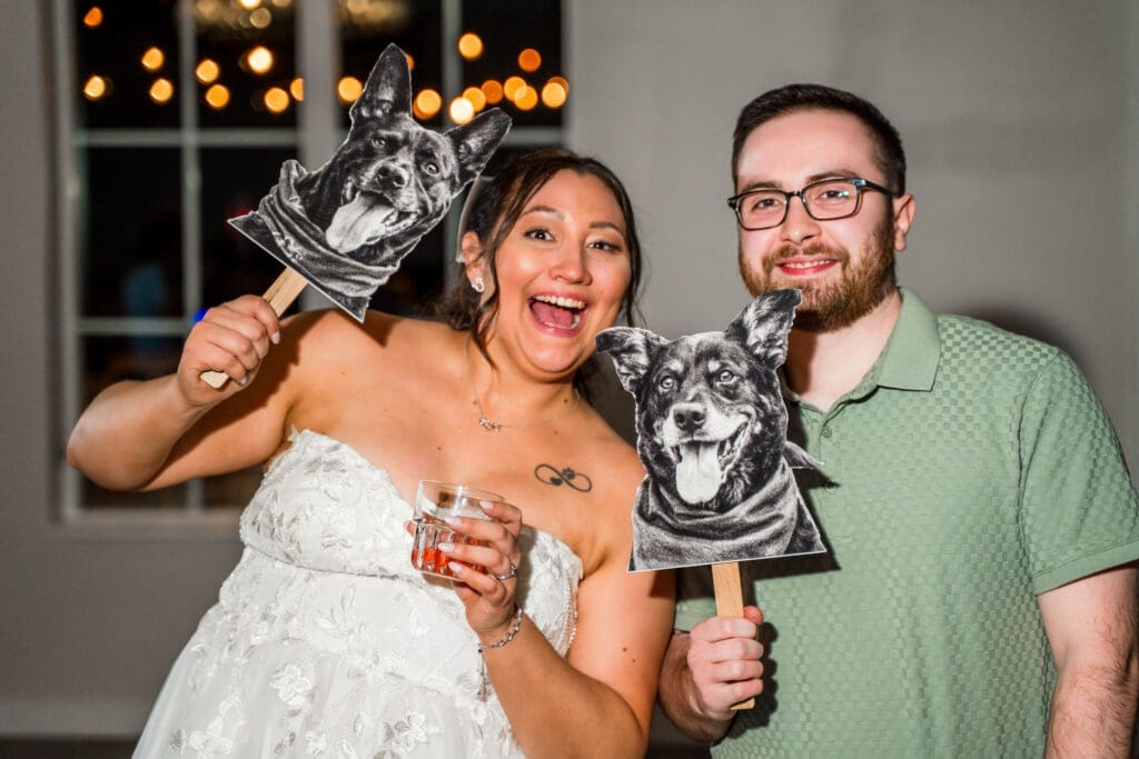 The bride and a guest holding up photos of her dogs
