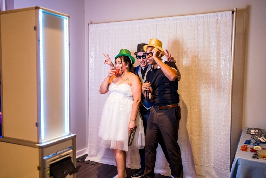 The couple and a guest use a photobooth at their wedding