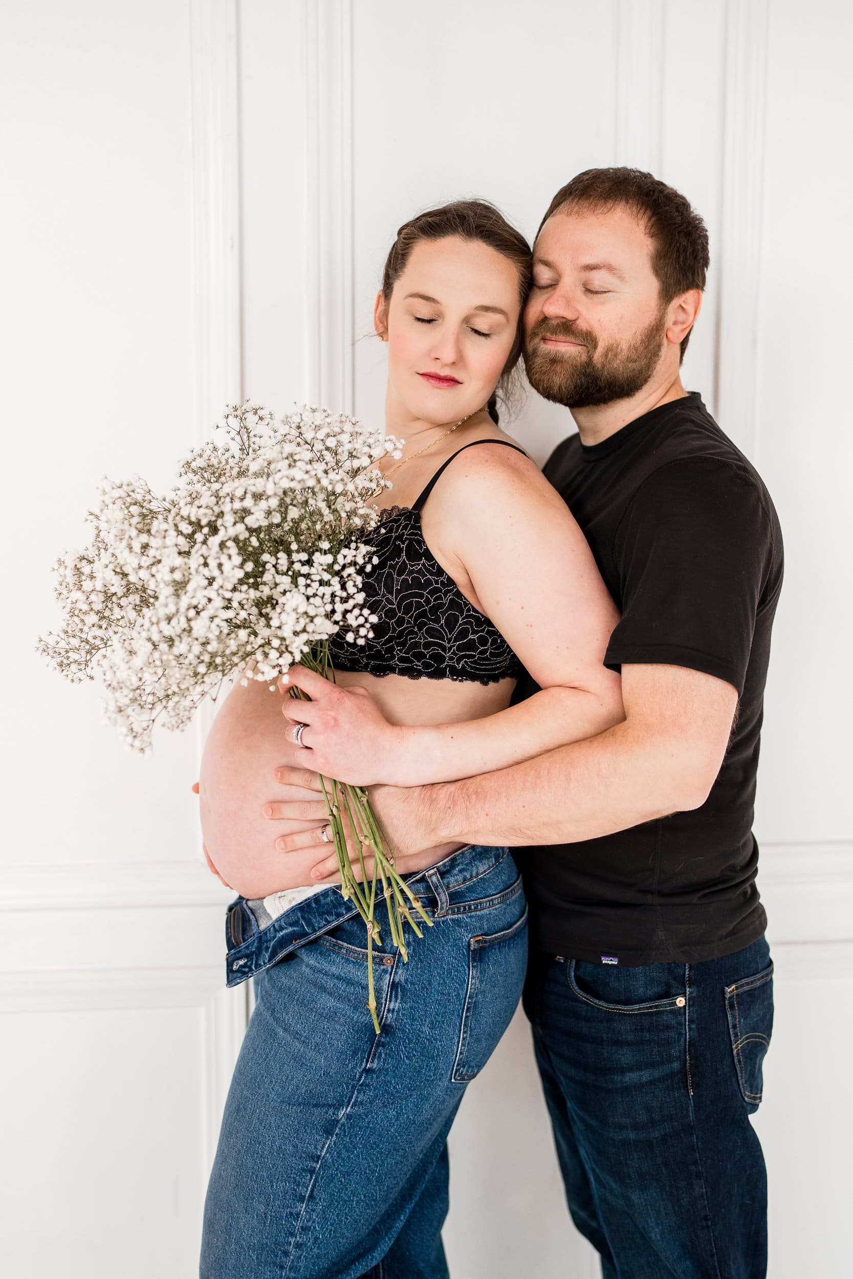 Casual maternity photo of a couple holding baby's breath flowers at a studio in Columbus Ohio