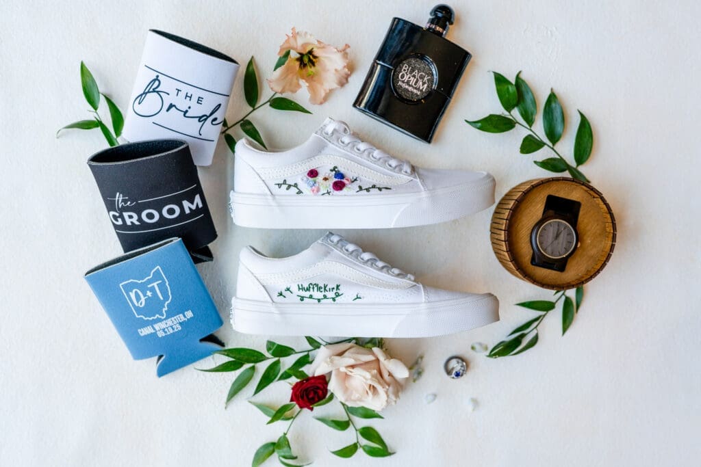 Reception flat lay including embroidered shoes, koozys, and more.