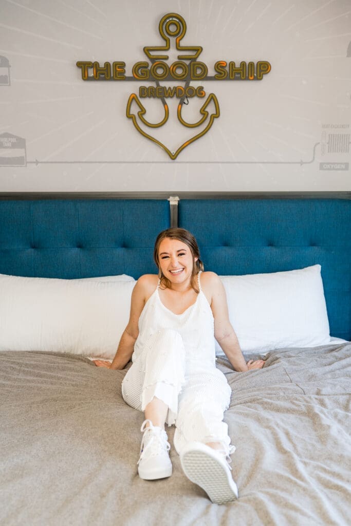 Bride in her getting ready outfit on the bed in her brewery hotel