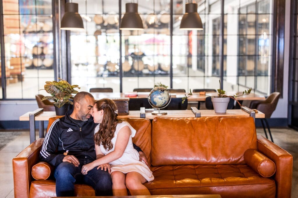 Bride and groom in casual outfits sit on a couch in front of the taproom at BrewDog in Columbus, Ohio