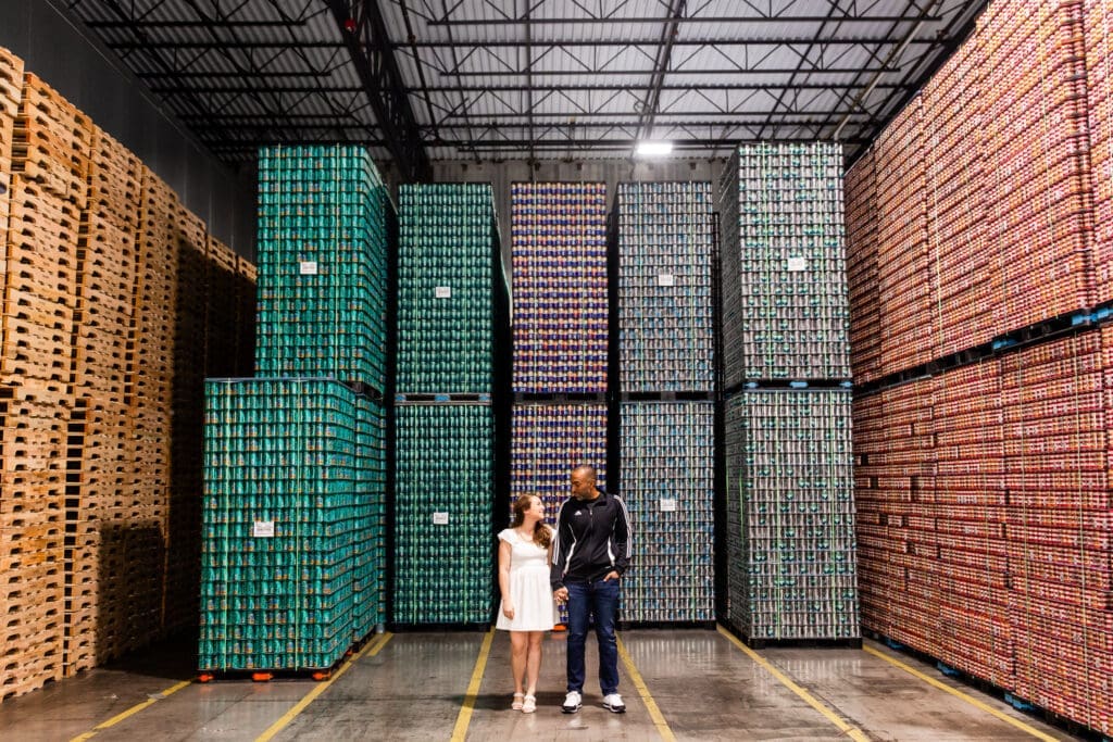 Bride and groom in casual outfits in front of pallets of beer at BrewDog in Columbus, Ohio