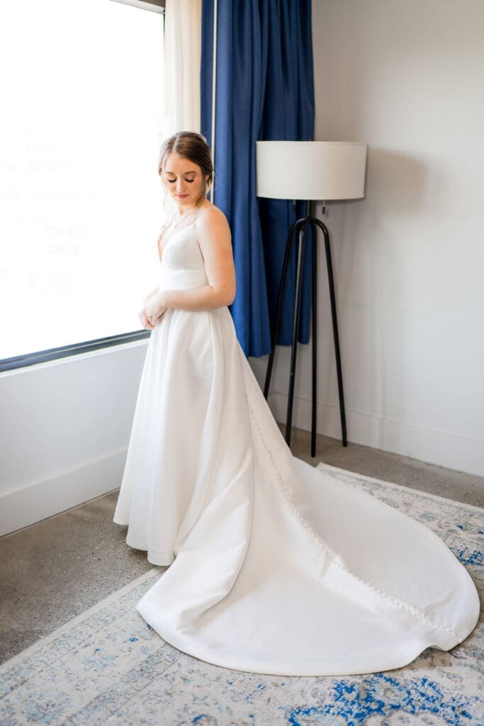 A bride poses by her hotel window with her train fluffed in Columbus, Ohio
