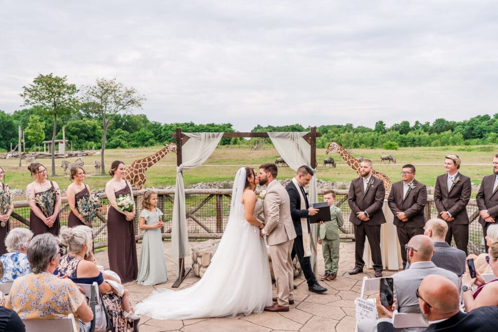 The first kiss with animals roaming in the background at a wedding ceremony at the Columbus Zoo and Aquarium