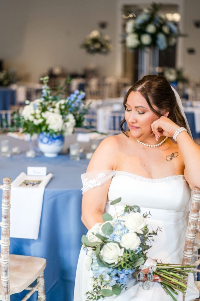 Editorial pose of the bride sitting at one of her reception tables at the Estate at New Albany