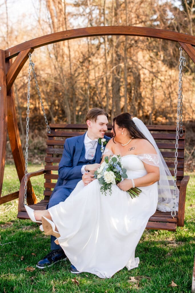The bride and groom sit on a bench swing at the Estate at New Albany