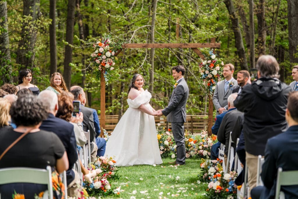 Guests take photos of the bride and groom at their ceremony arch at the Dempsey Event Center in Delaware, Ohio.
