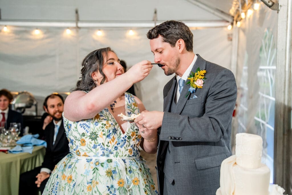 Bride feeds the Groom cake at their tented wedding reception at the Dempsey Event Center in Delaware, Ohio.