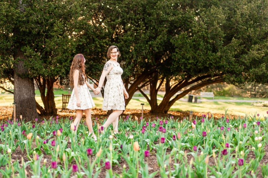A LGBTQ+ couple holding hands at Inniswoods Metro Gardens amongst the tulips