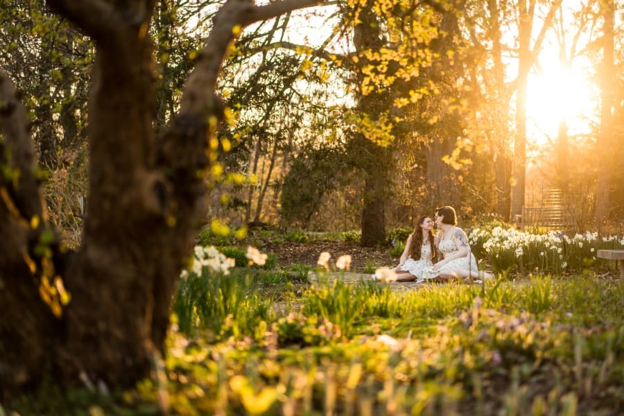A golden hour spring engagement photo of a LGBTQ+ couple at Inniswoods Metro Gardens