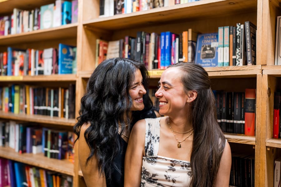 Two women smile at each other during their engagement session at the Book Loft in Columbus, Ohio.