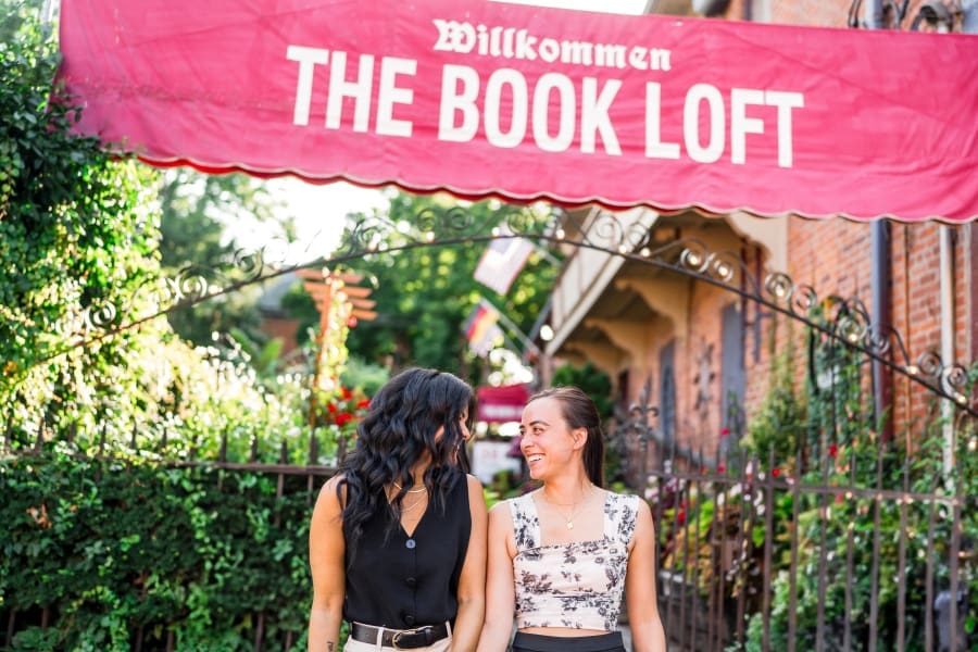 Two women walk together at their engagement session at the Book Loft in Columbus, Ohio.