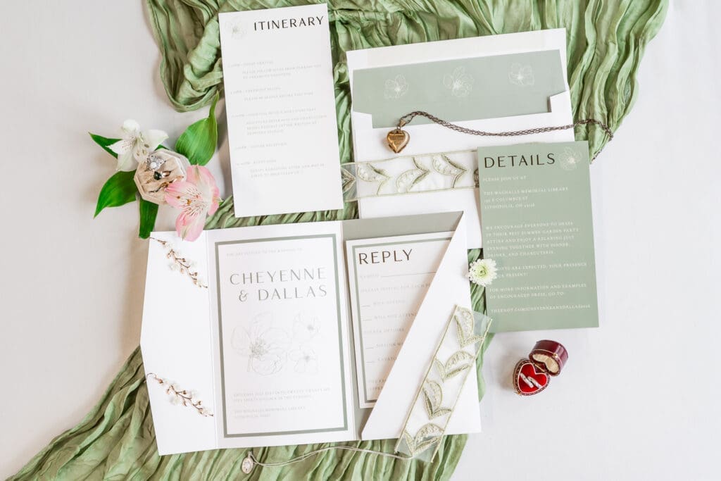 Flat lay detail photo with invitations, jewelry, and rings with a whimsical garden vibe